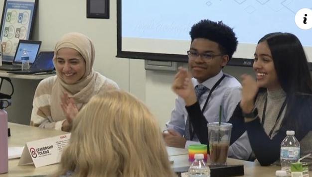 Students sitting around a table smile during a discussion