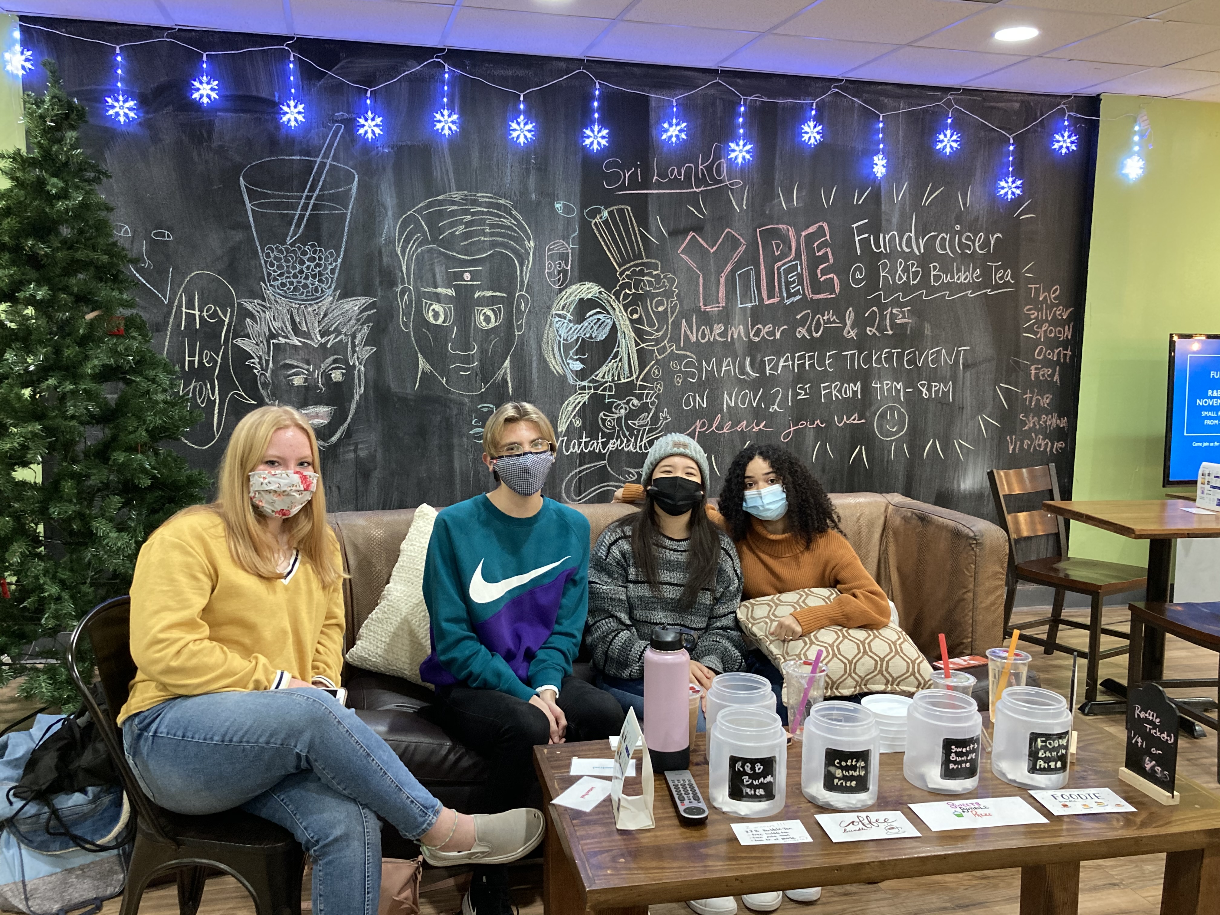 Students in face masks smile at the camera during a bubble tea fundraiser